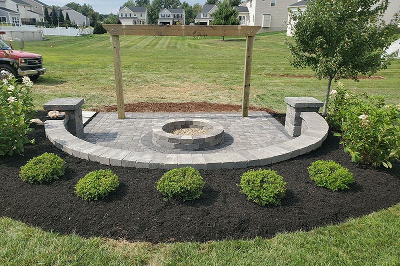 Outdoor firepit with stone seating structure and frame for swing